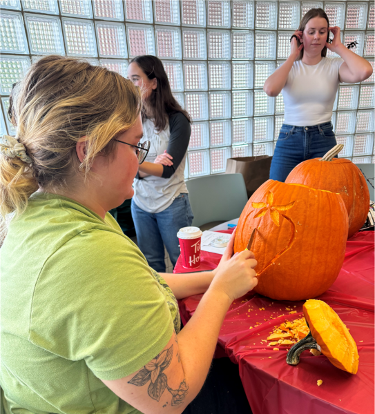 Grad student carving a strawberry in her pumpkin